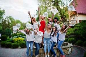 bachelorette party NYC: Comany of young women posing outside with inflated condoms at bachelorette party.